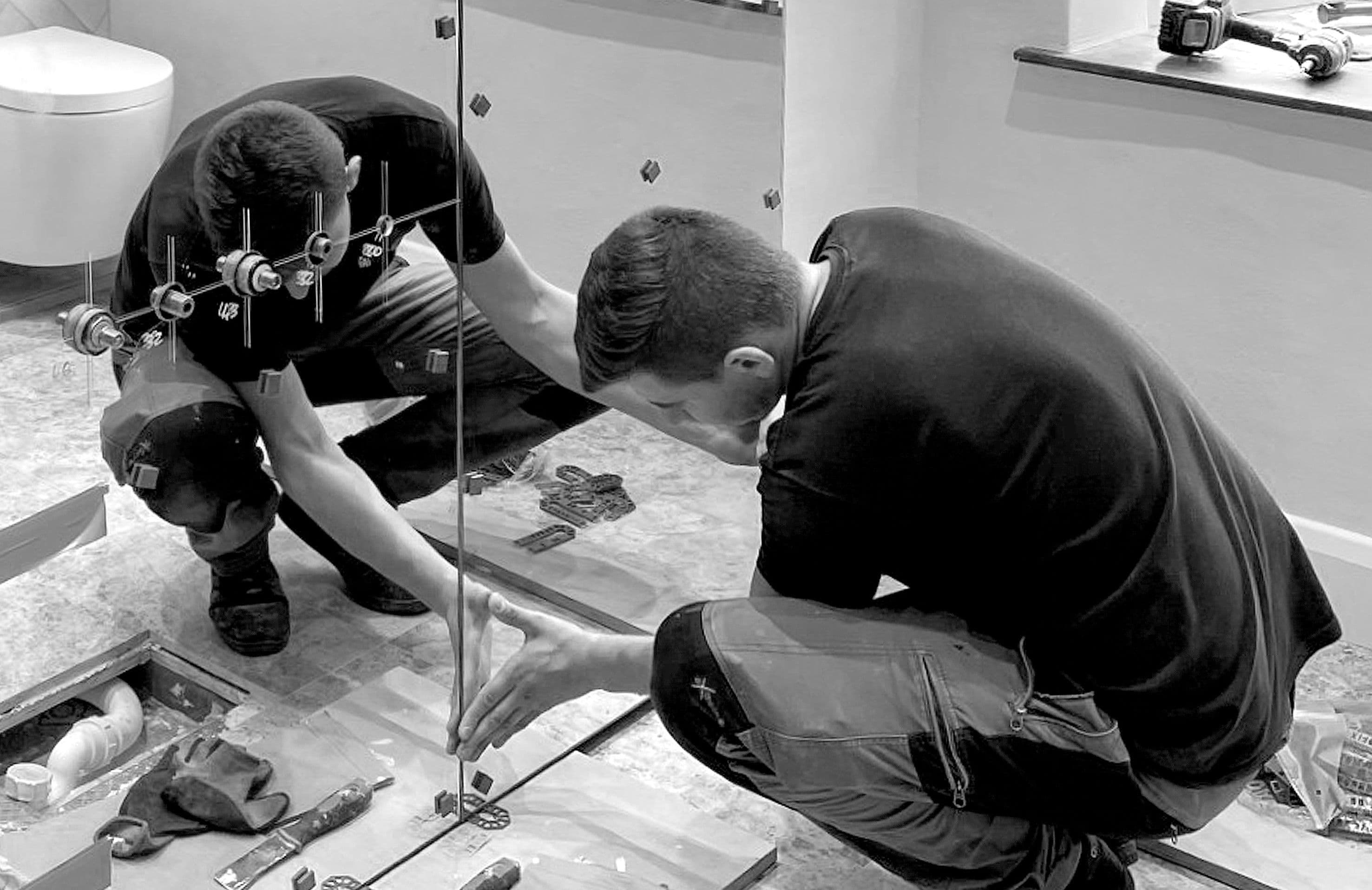 Man fitting mirror to bathroom wall