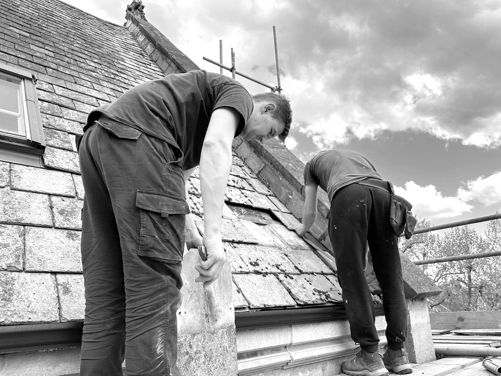 men fitting roof tiles on church